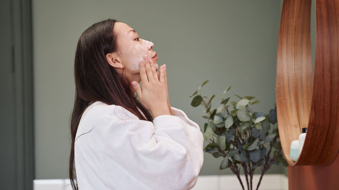 Best SPF for sensitive skin - woman applying cream in front of mirror