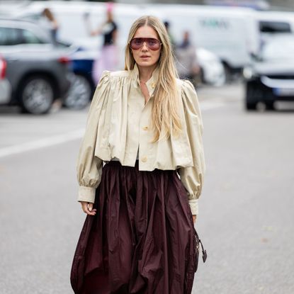 a guest at copenhagen fashion week wearing a beige jacket and brown skirt