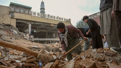 People dig through the wreckage after the 30 January bombing of a Peshawar mosque 