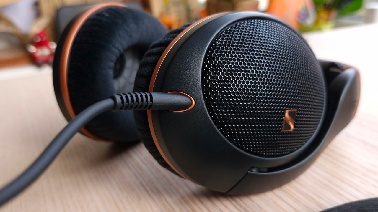 A side-on photograph of the Sennheiser HD 505 headphones in black and copper, showing the cable. The headphones are on a wooden surface.