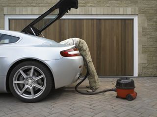 man bending over into car with vacuum cleaner