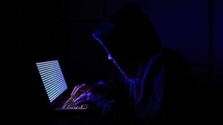 DDoS attack set up from the enemy side: Internet hacker sits in dark room