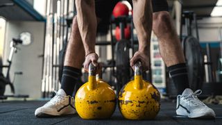 a photo of a man holding two kettlebells