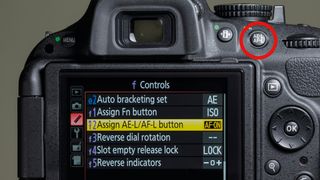 The rear screen of a Nikon camera showing the f Controls menu and 'Assign AE-L/AF-L button' option, with a red circle highlighting the AE-L/AF-L button