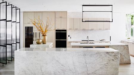 modern kitchen with stone benchtop, glass doors, beige cabinets, and lighting