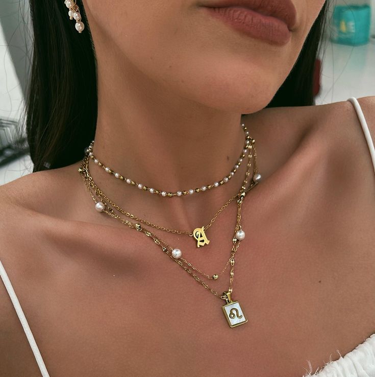 Pearl choker necklace layered with a longer spaced pearl necklace and a Leo star sign pendent.