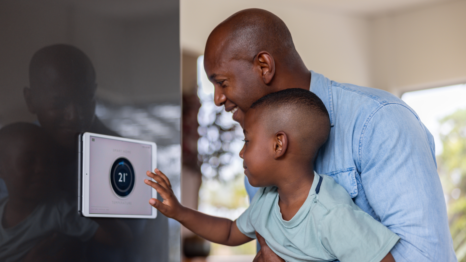father and son adjusting heating temperature panel on wall