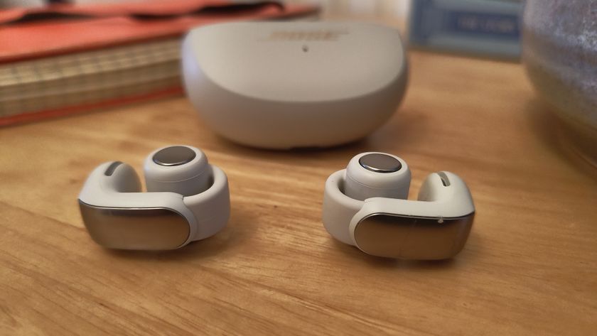 Bose Ultra Open Earbuds on a wooden table