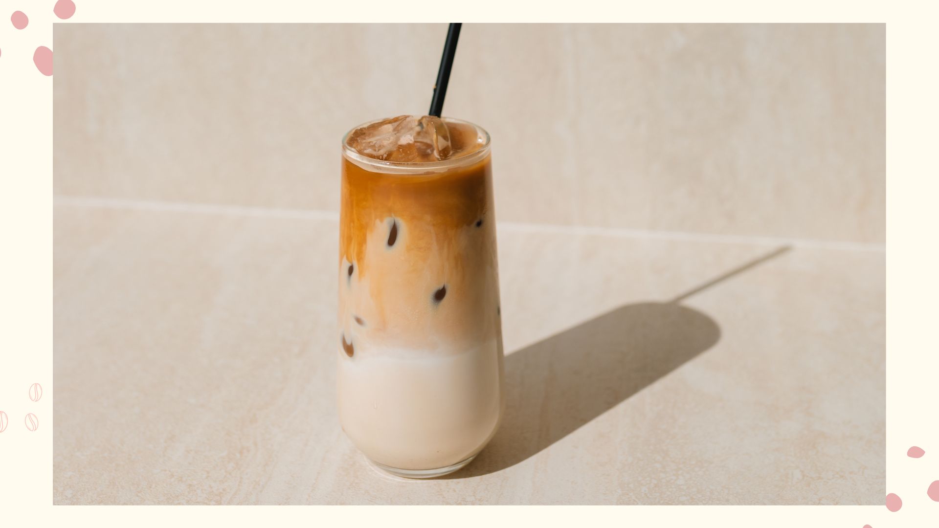 An iced coffee on a marble background with coffee illustrations on the side