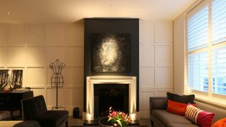 living room at night with white fireplace and downlights