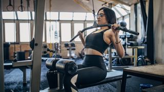 Woman performs the lat pull-down in a gym