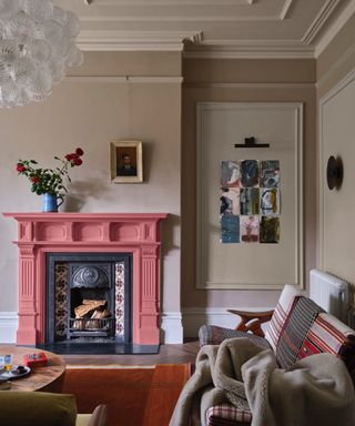 neutral living room with coral painted fireplace, striped couch, artwork, paneling, rug, coffee table, blankets, Farrow & Ball