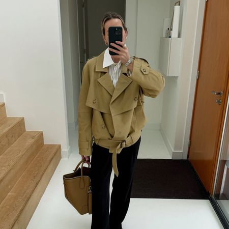 fashion influencer @anoukyve wearing a cropped trench coat with black jeans