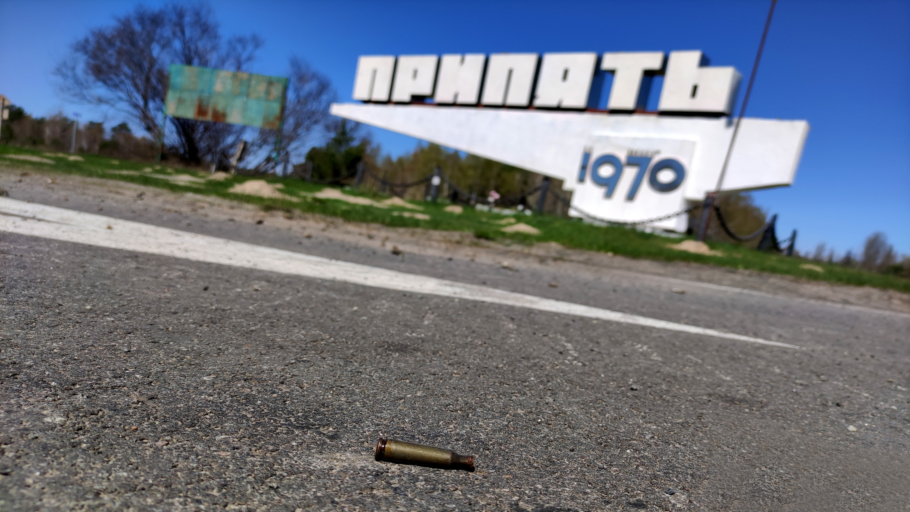 A spent bullet cartridge lies on the asphalt near the sign that marks the limits of the ghost town of Prypiat. The area was the scene of intense fighting during the first days of Russia's invasion of Ukraine.