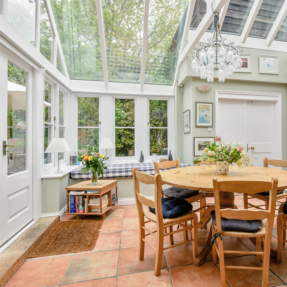 white garden room with wooden dining table and flower vase
