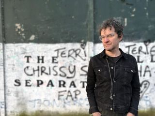 Mark Cousins in front of a graffiti-sprayed wall