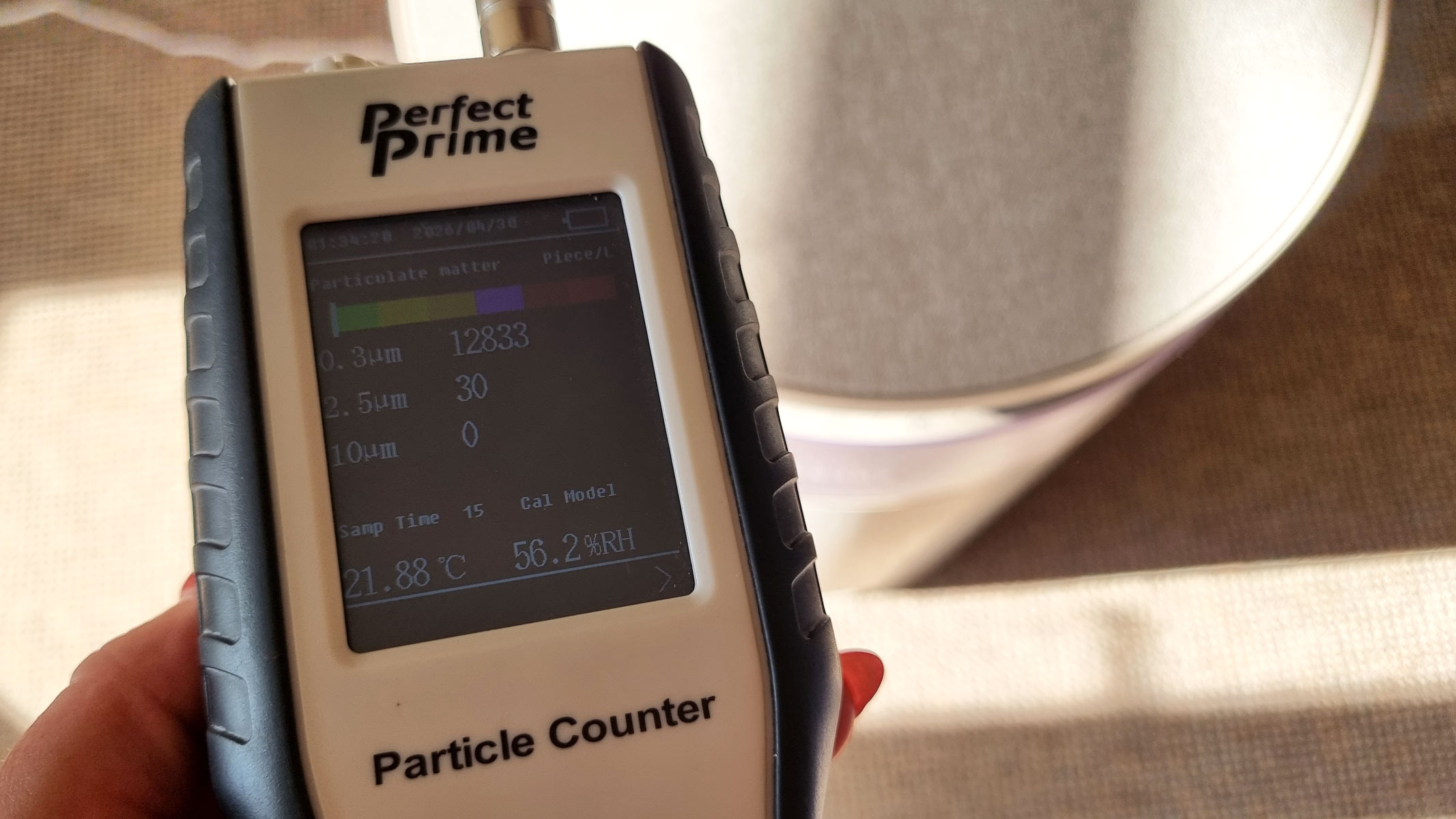 a close-up picture of our reviewer testing the Dreame FP10 air purifier using a Perfect Prime air particle monitor