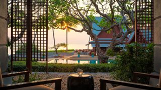 Two chairs overlooking a pool and a beach at the luxury Chiva Som retreat