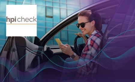 Woman wearing sunglasses in the driver's seat with her phone in her hand