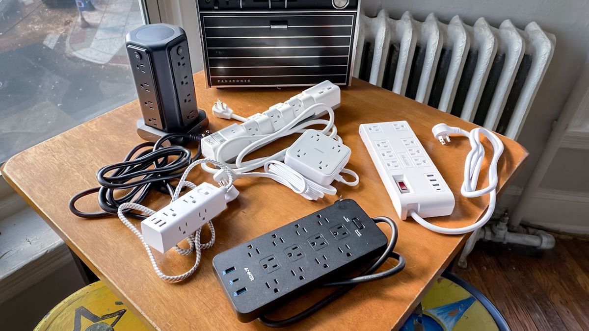 A pile of surge protectors on a table