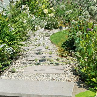 garden pathway with gravel and stone slabs bordered by flowering plants