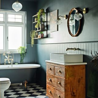 a dark green bathroom with green panelling and a traditional roll-top bath