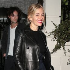 Sienna Miller exits a restaurant wearing Missoma waves earrings with a leather trench coat.
