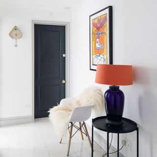 hallway with white wall and lamp on stool and white chair