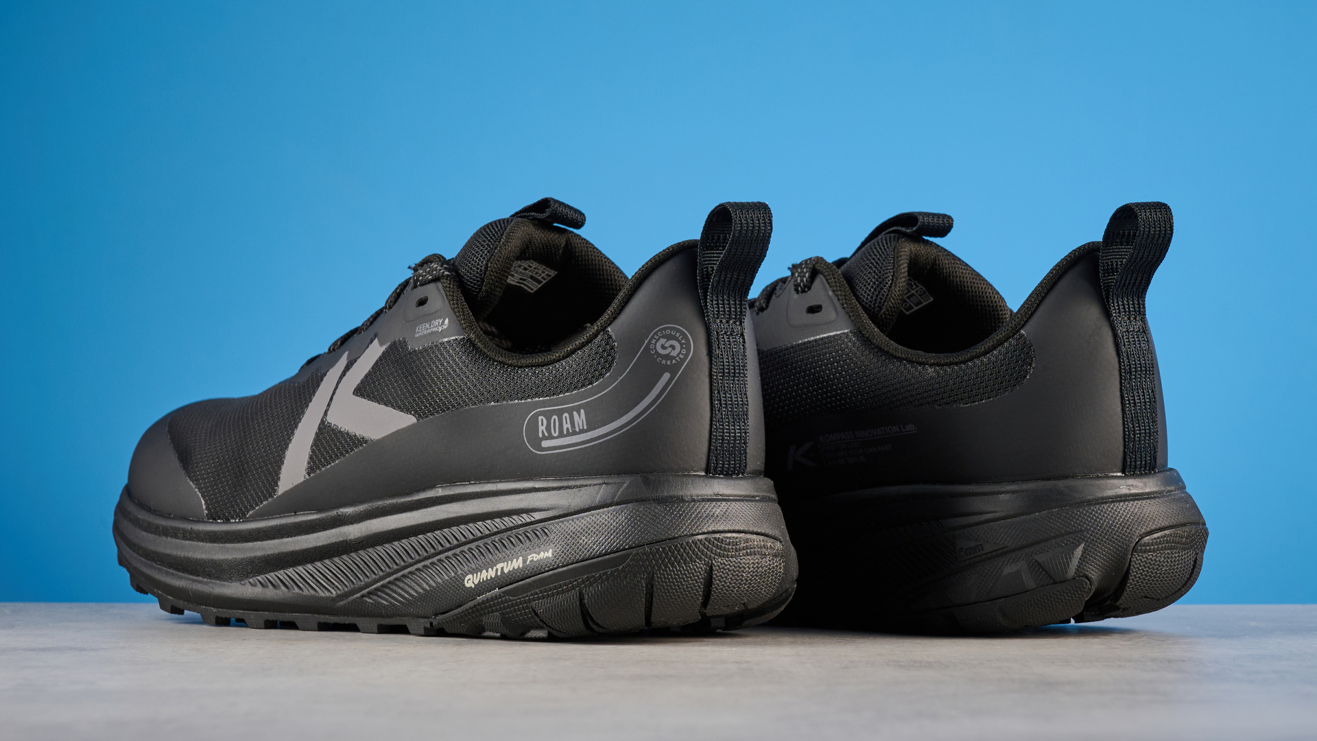 Keen Roam train running shoes in black photographed in front of a blue background
