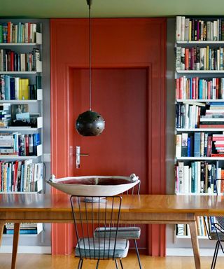 red door and border in a dining room with many bookshelves