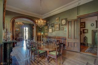 A gothic dining room with green walls and a large wooden oval dining table