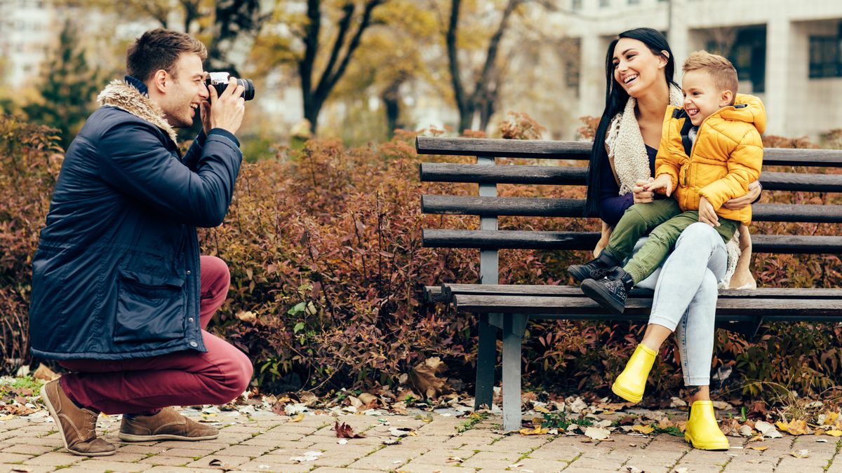 Young father photographing his son and wife in the park