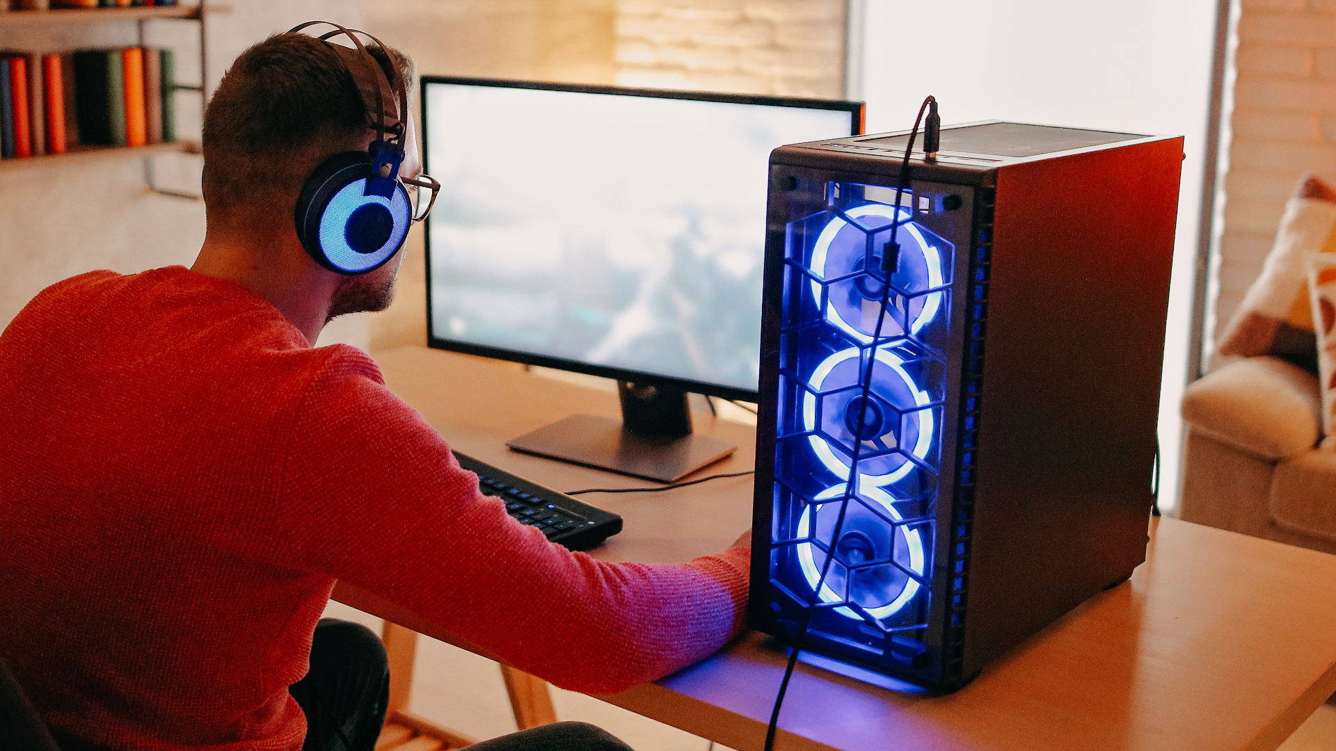 A man in a red jumper playing PC.