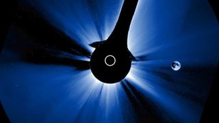 A black circle has a ring of white in it as it covers the center of the image, with blue and white light streaking out from the middle of the photograph