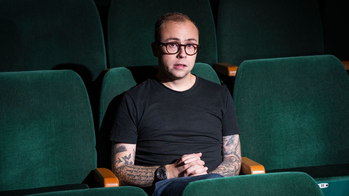 Joe Tracini sitting on a green chair with a light shining on him.