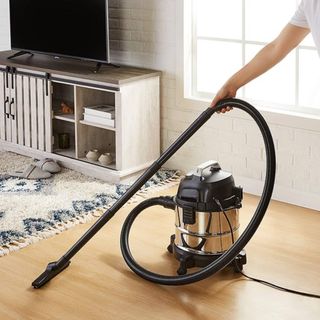 Stainless steel wet and dry vacuum cleaner with long arm on wooden flooring and rugged area