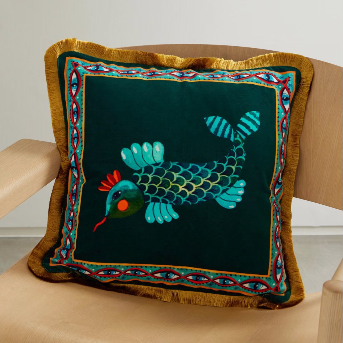 A black cushion with a fish motif in a bright olo blue/green