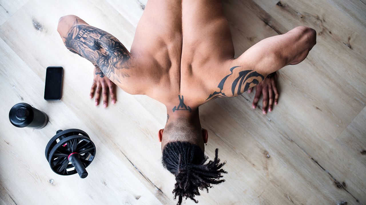 A portrait of fit mixed race man with dreadlocks doing exercise at home, view from directly above