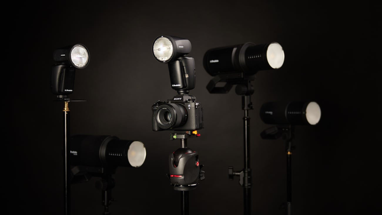A Sony camera stands among several Profoto studio lights on stands, set against a dark background