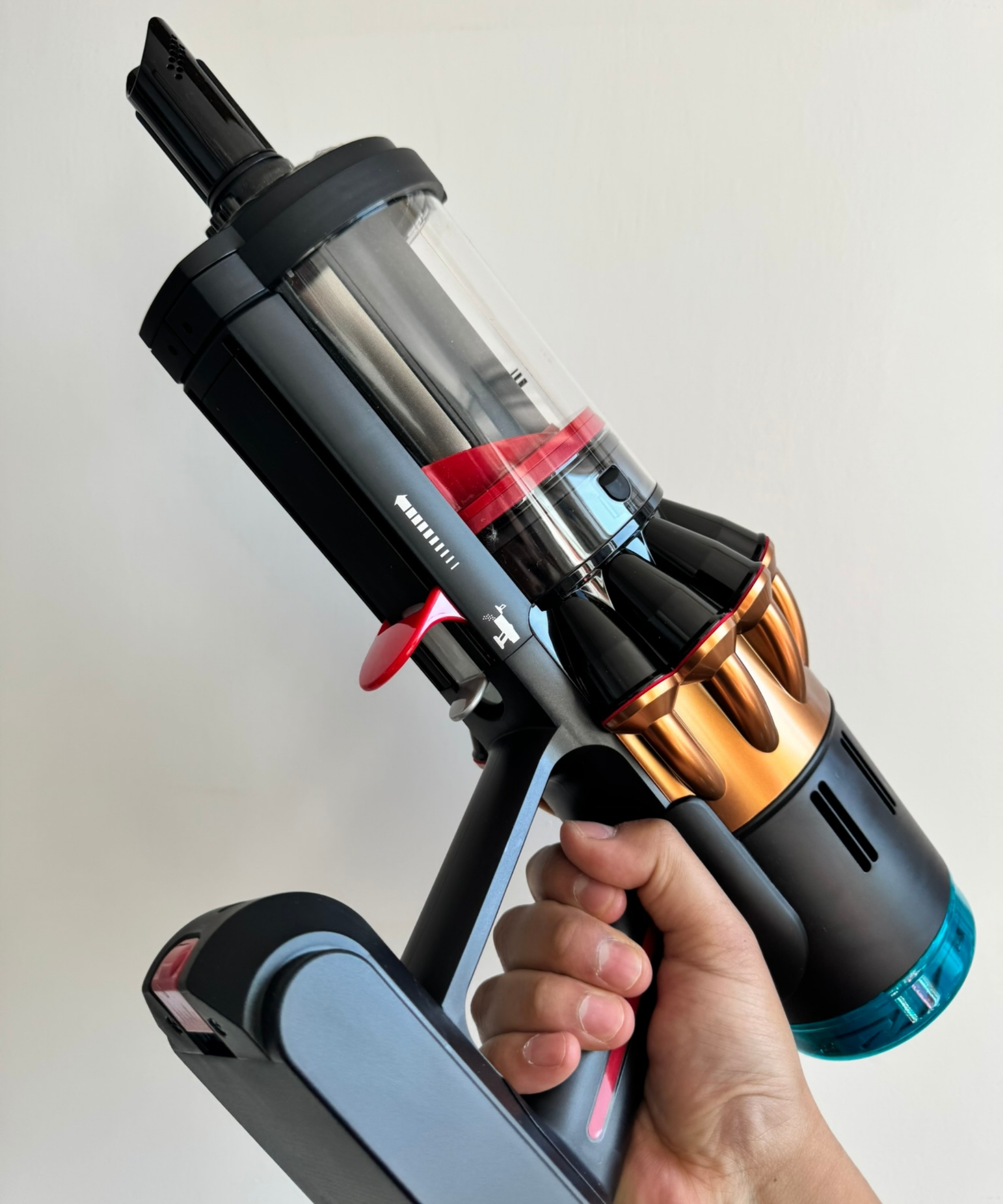 Dyson V16 Piston Animal cordless vacuum cleaner held in hand in front of white wall.