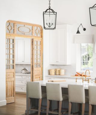 white kitchen with vintage wooden pantry doors and black lantern lighting