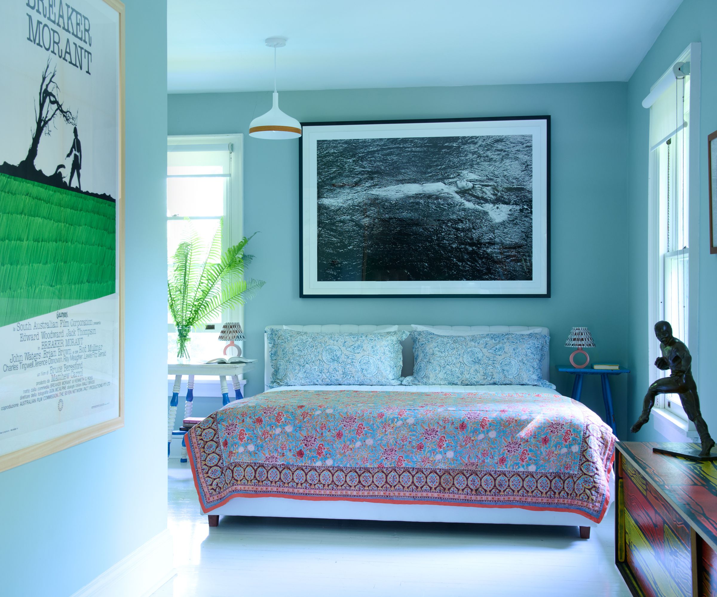 blue bedroom with large artwork and patterned bedding