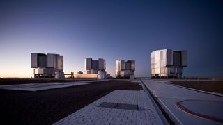 four large structures stand on a flat ground with a clear sky above.