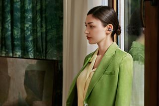 woman in green blazer stands side on