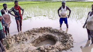 Locals crows around a crater created by the possible football-sized meteorite that fell in a rice field in the Mahadeva Village of the eastern state of Bihar in India. 