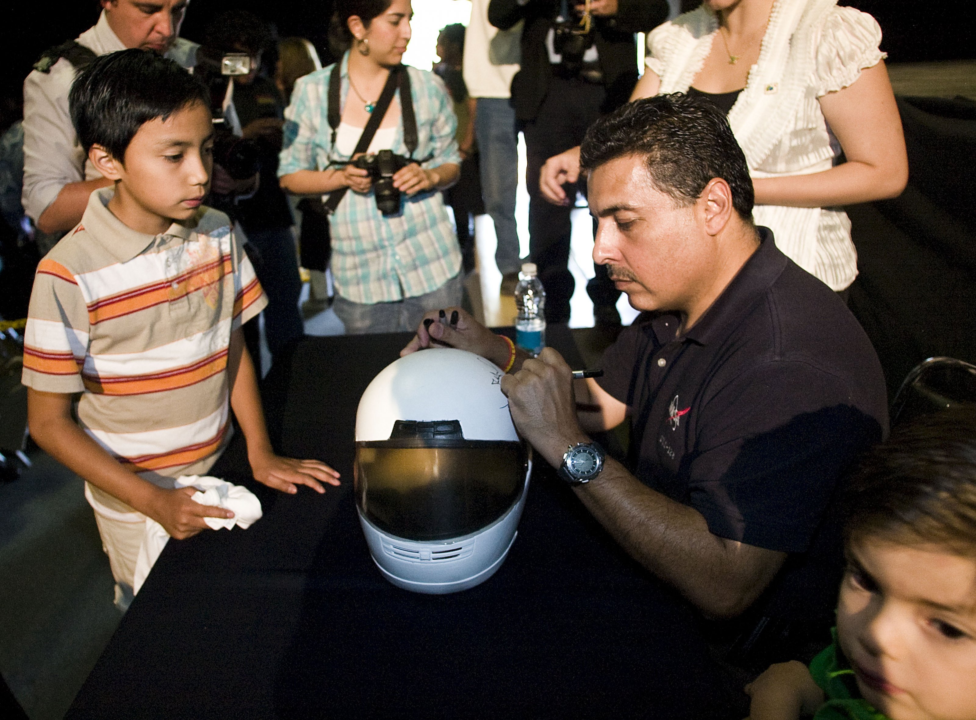 an astronaut signs a toy helmet for a child