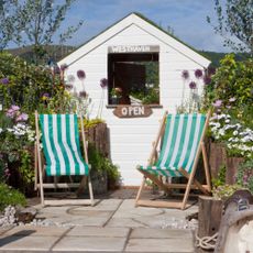 striped deckchairs and white shed in garden