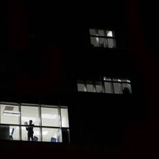 man works late in office building at night