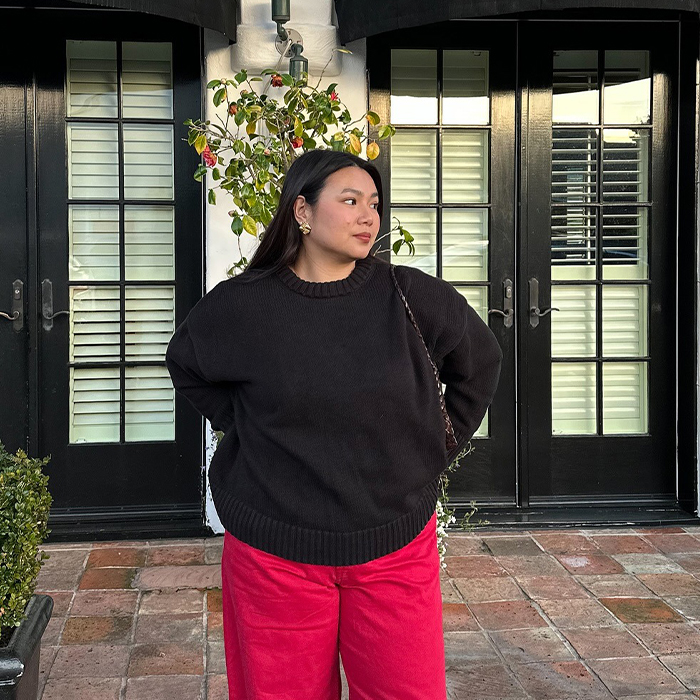 marina wears black sweater, red pants, and black flats while posing