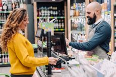 A woman pays for her groceries at the cash register using a credit card.